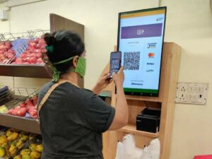 This image shows a woman making contactless payments via a QR code as one of the retail customer experience strategy