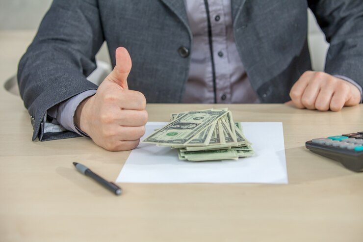 The image shows a Businessman in a suit giving a thumbs-up while holding cash. 